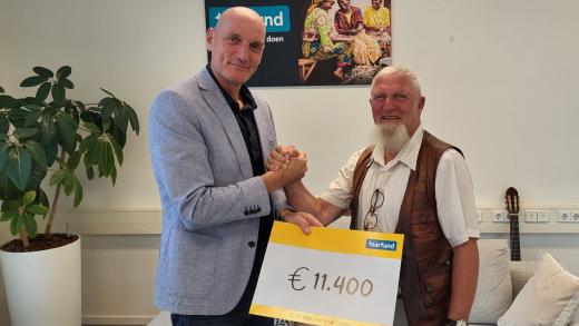 Jan overhandigt de opbrengst van zijn sponsortocht aan directeur Guido de Vries.
