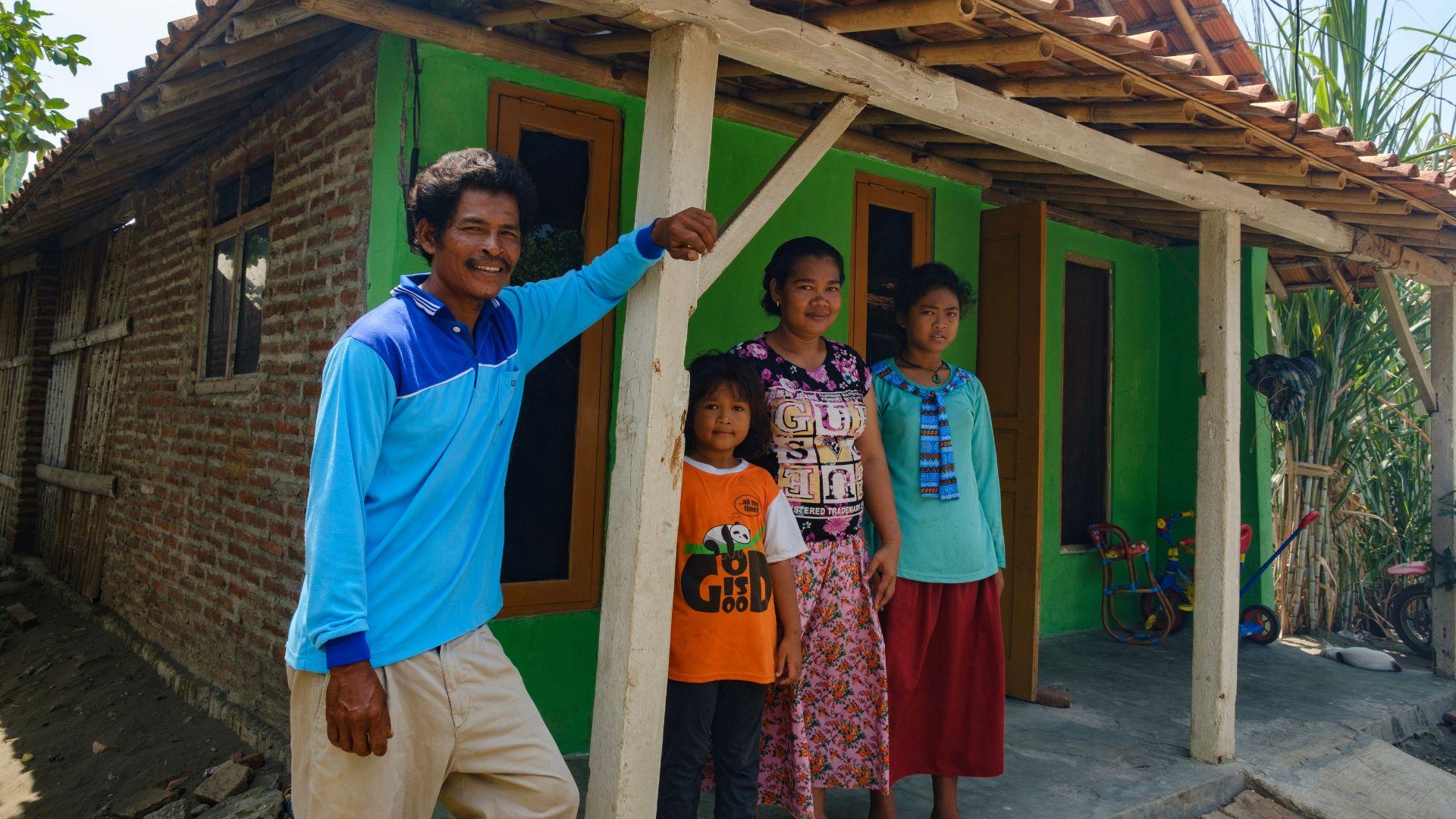 Sutarno met zijn gezin voor hun nieuwe huis met stenen muren