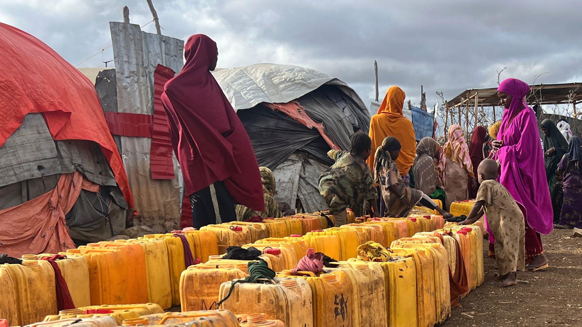 In een kamp voor ontheemden staan mensen in de rij om water te halen