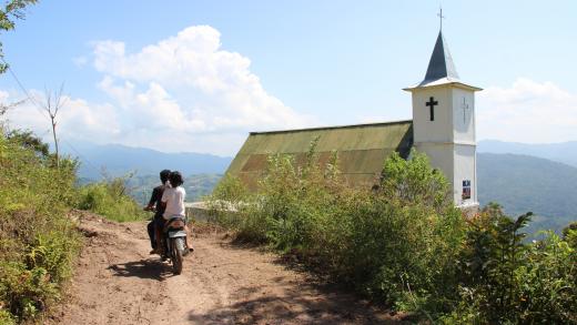 Twee personen op scooter langs een kerk in Indonesie