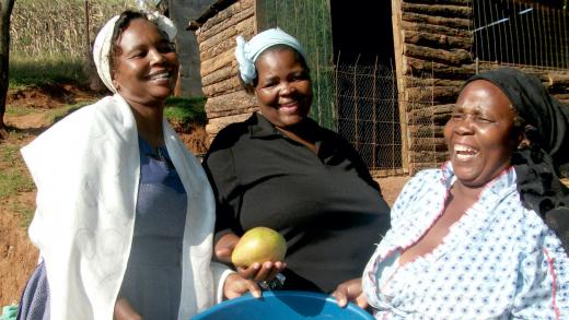 Drie lachende vrouwen met de opbrengt van het land in Zuid-Afrika