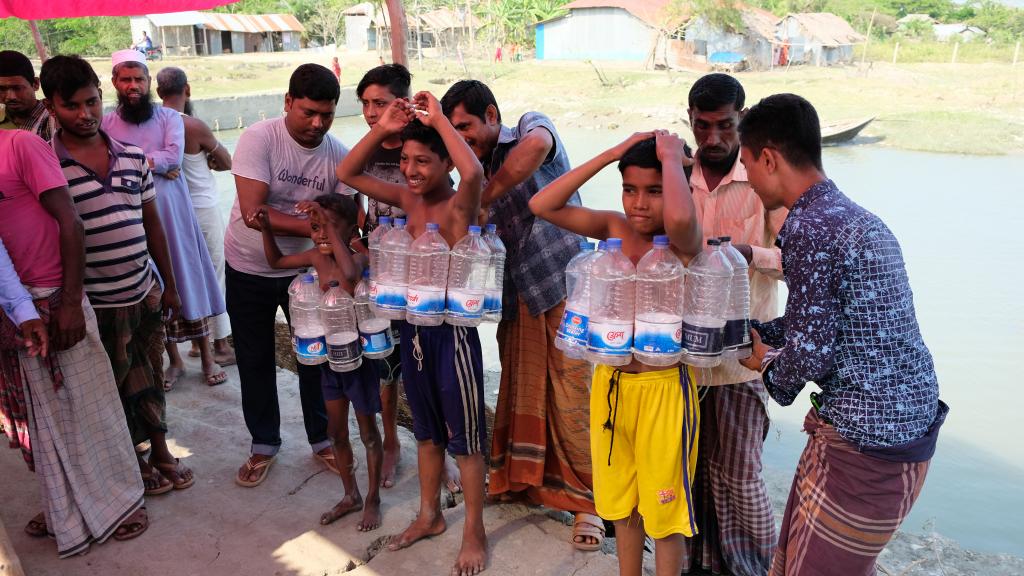 Jongens leren hoe ze een zwemvest van plasticflessen moet dragen
