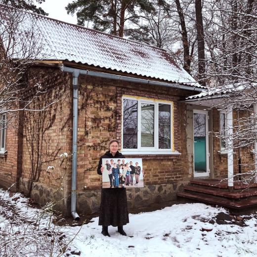Hanna met een foto van haar gezin voor haar herstelde huis