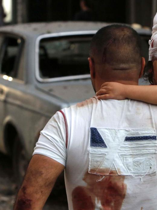Gewond kind wordt gedragen door man in Beiroet, Libanon