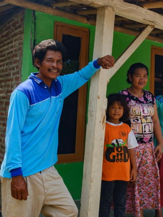 Sutarno met zijn gezin voor hun nieuwe huis met stenen muren