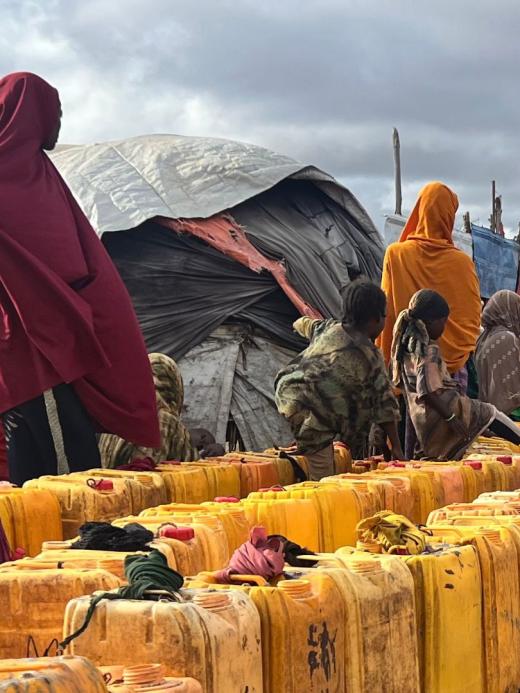 In een kamp voor ontheemden staan mensen in de rij om water te halen